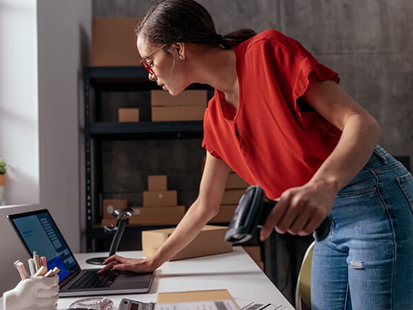 Business Solutions Retail Features 600x450 Woman looking at laptop and holding tag scanner