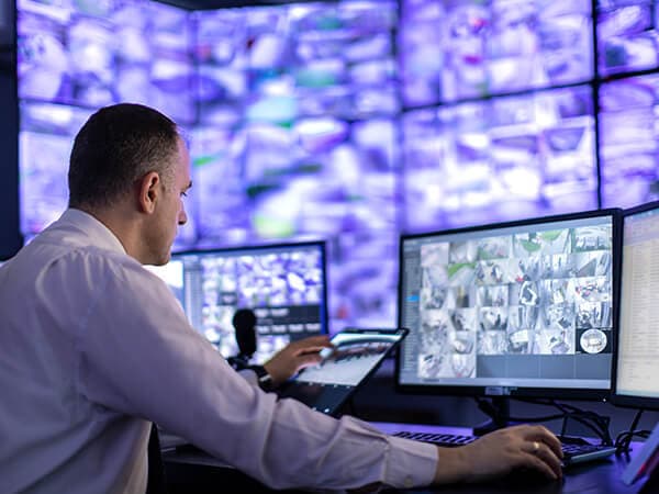 Business Business Cloud Access Features 600x450 Man sitting at desk looking at computer while other computers are hanging up on the wall