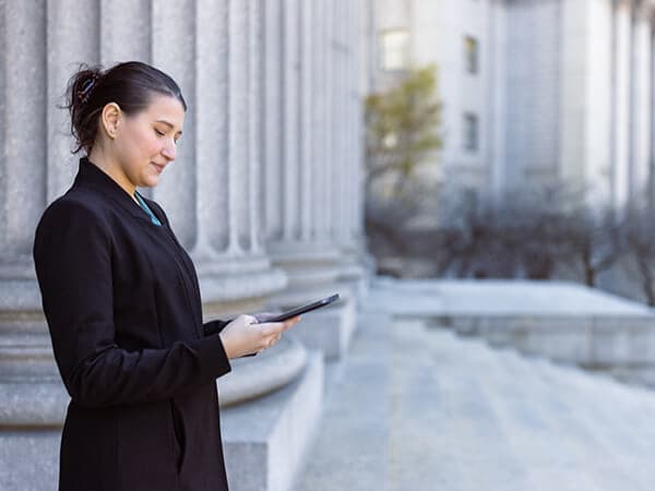 Business Federal Government Solutions Features 600x450 Worker outside a government building looking at mobile phone
