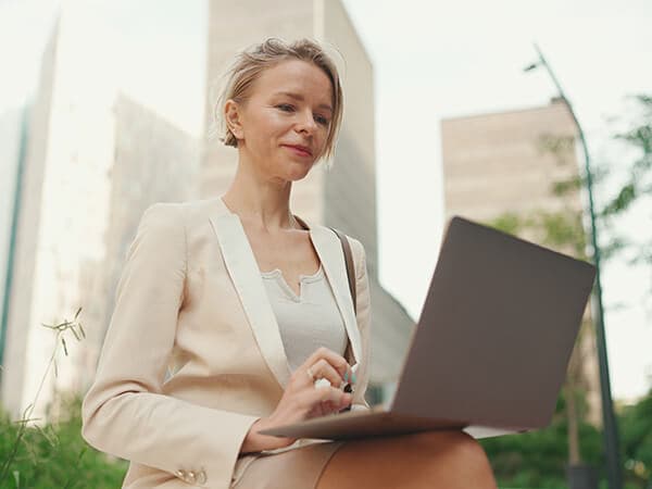 Business Higher Education Features 600x450 Professional woman sitting outside working on a laptop