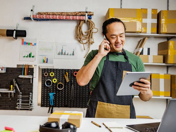Business SMB Solutions Feature Hero 600x450 Man in shop talking on phone and looking at tablet