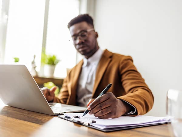 Business Single site enterprises Features 600x450 Man taking notes with laptop in front of him
